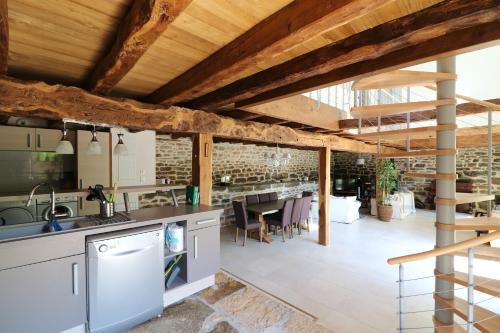 uma cozinha em plano aberto e sala de jantar com tectos em madeira em Maison de 3 chambres avec jardin amenage et wifi a Thegra em Thégra