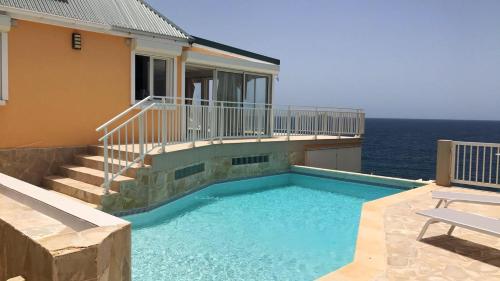 a house with a swimming pool next to the ocean at 2 bedrooms villa at Saint Barthelemy 500 m away from the beach with sea view private pool and terrace in Saint Barthelemy