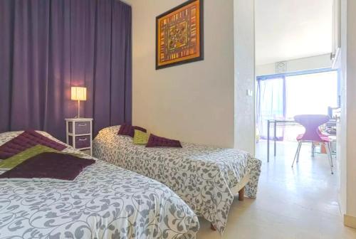 テウル・シュル・メールにあるAppartement d'une chambre avec vue sur la mer terrasse amenagee et wifi a Theoule sur Merの紫色のカーテンが備わるホテルルームのベッド2台