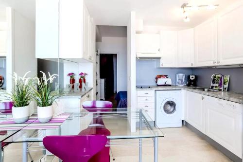 une cuisine avec une table en verre et des chaises violettes dans l'établissement Appartement confortable à Théoule-sur-Mer, 30 m², vue mer., à Théoule-sur-Mer