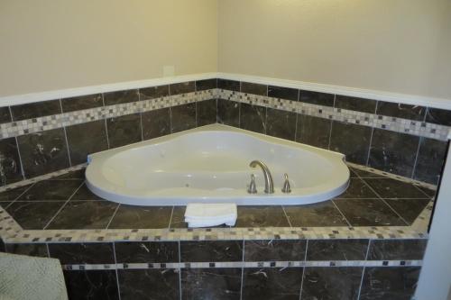 a bath tub in a bathroom with black tile at American Inn Stockton in Stockton