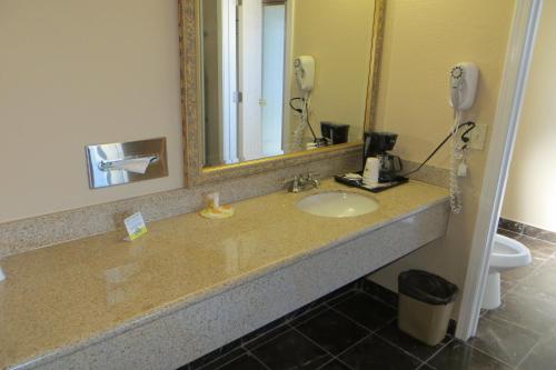 a bathroom with a sink with a mirror and a phone at American Inn Stockton in Stockton