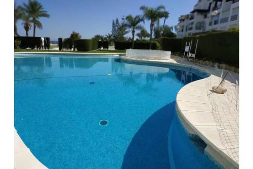 ein großer blauer Pool mit Palmen im Hintergrund in der Unterkunft Spacious house in Roquetas de Mar, 140 m², shared pool in Roquetas de Mar