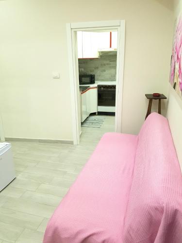 a pink bed in a room with a kitchen at Charming apartment in Canicatti, 40 m² with private terrace. in Canicattì