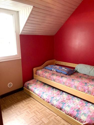 deux lits dans une chambre avec un mur rouge dans l'établissement Maison accueillante à Betpouey avec superbe terrasse, à Betpouey