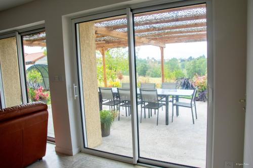 una puerta de cristal que da a un patio con mesa y sillas en Villa élégante à Panissières avec piscine privée, en Panissières
