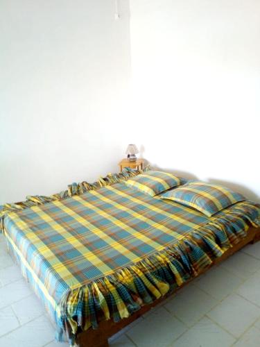 a bed with a plaid blanket on top of it at Maison confortable avec jardin à Basse-Terre + Parking inclus in Basse-Terre