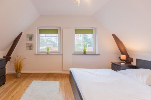 a bedroom with a bed and two windows at Charmantes Stadthaus in Husum