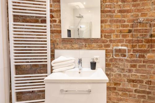 a bathroom with a white sink and a brick wall at Husumer Wasserturm - Ferienwohnung 1 in Husum
