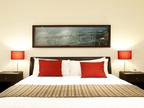 a bedroom with a bed with red pillows and two lamps at The Waves Apartments in Cowes