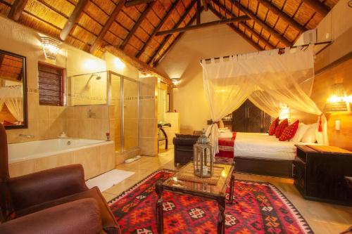 a bedroom with a bed and a tub in a room at Khaya Umdani Guest Houses in Marloth Park