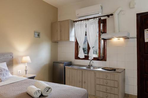 a small kitchen with a sink and a bed at Kasteli Studios & Apartments in Panormos Rethymno