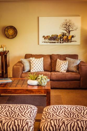a living room with a brown couch and a table at Bushveld Terrace Safari Hotel, Lodge & Spa in Phalaborwa