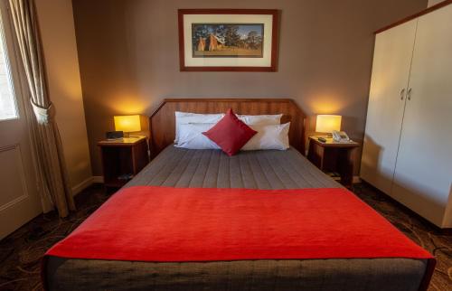 a bedroom with a bed with a red blanket on it at Quality Hotel Bayswater in Perth
