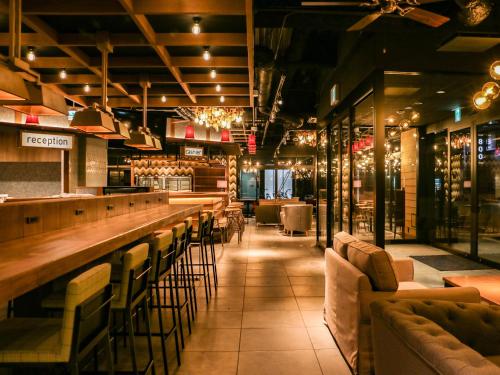 a restaurant with a bar with chairs and wine bottles at UMEDAHOLIC HOTEL in Osaka