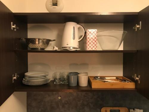 - une étagère de cuisine avec des assiettes et des ustensiles dans l'établissement Studio cosy Disney/Paris. RER Val d’Europe à 150m, à Montévrain