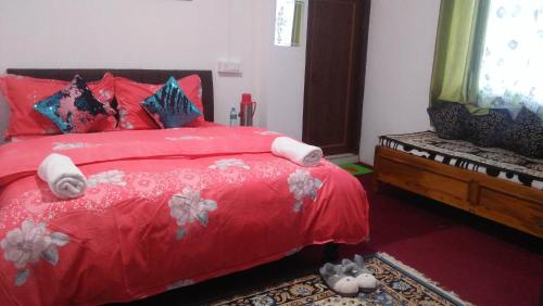 a bedroom with a red bed with red pillows at shalom inn home stay in Darjeeling