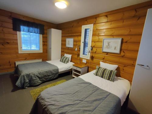 two beds in a room with wooden walls at Rauhalahti Holiday Homes in Kuopio