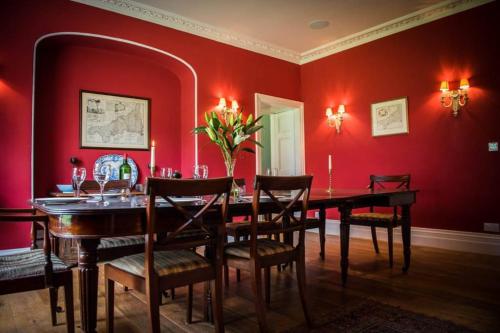 a dining room with red walls and a table and chairs at The Manor House at Boconnion in Bodmin