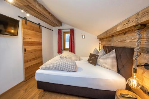 1 dormitorio con 1 cama grande y pared de madera en sWiederkehr en Schladming