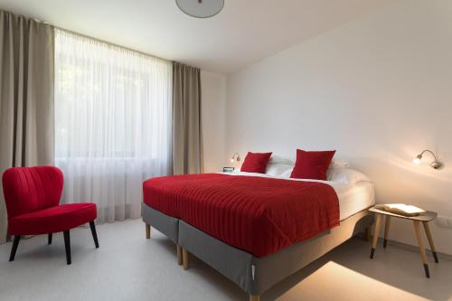 ein Schlafzimmer mit einem roten Bett und einem roten Stuhl in der Unterkunft Vila48 in Ostrava