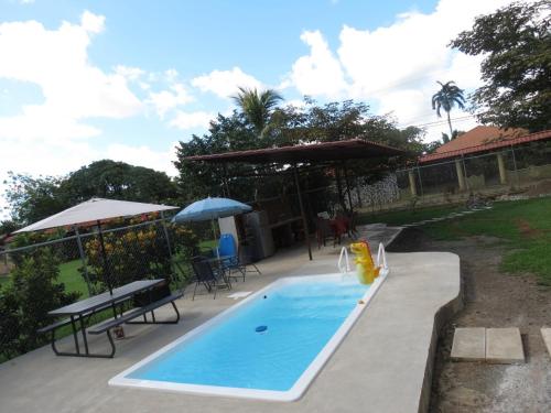 una piscina con mesas, sillas y una sombrilla en Villa Segura Manuel Antonio, Quepos en Quepos