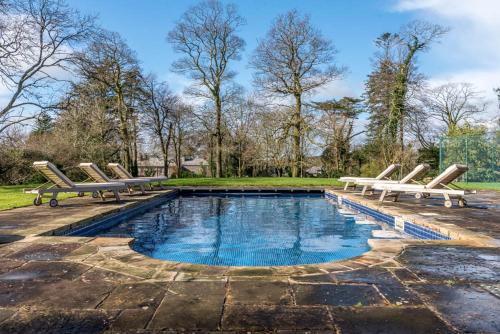 a swimming pool with two lounge chairs and a pool at The Manor House at Boconnion in Bodmin