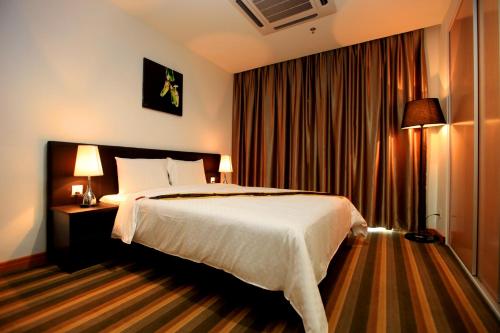 a hotel room with a bed and two lamps at Merdeka Suites Hotel in Miri