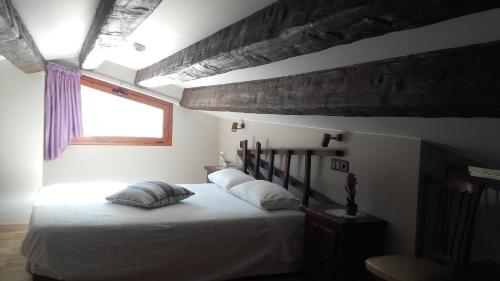 una camera da letto con un letto con lenzuola bianche e una finestra di Casa Rural Cal Xico ad Adrall