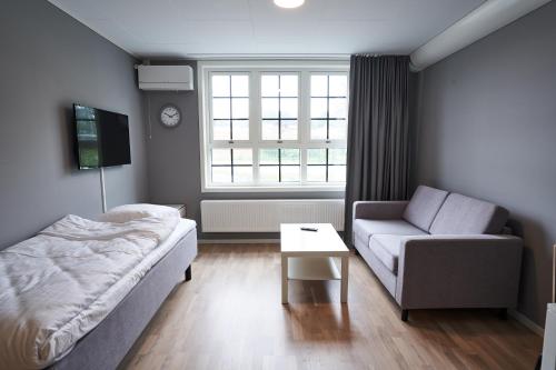 a bedroom with a bed and a couch and a window at Ekebyhov Hotell in Ekerö