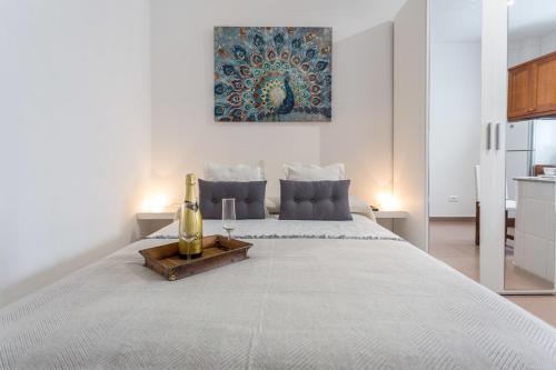 a white bedroom with a large bed with a bottle on it at Studio near the Sea and City in Las Palmas de Gran Canaria
