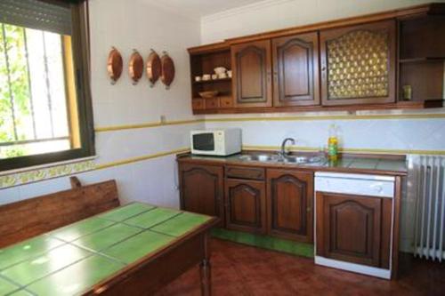 a kitchen with wooden cabinets and a sink and a table at 6 bedrooms house with enclosed garden at Ivanrey in Ciudad-Rodrigo