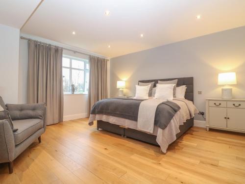 a bedroom with a bed and a chair and a window at The Little Paddock in Malmesbury