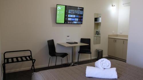 a room with a table and chairs and a tv on the wall at Loddon River Motel Kerang in Kerang