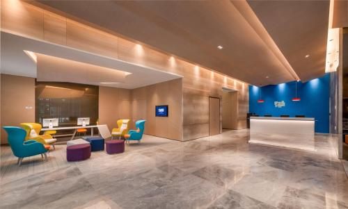 a lobby with yellow and blue chairs and a table at Holiday Inn Express Linyi North New District by IHG in Linyi