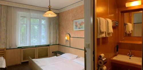 Schlafzimmer mit einem Bett, einer Badewanne und einem Waschbecken in der Unterkunft Hotel Hadrigan in Wien
