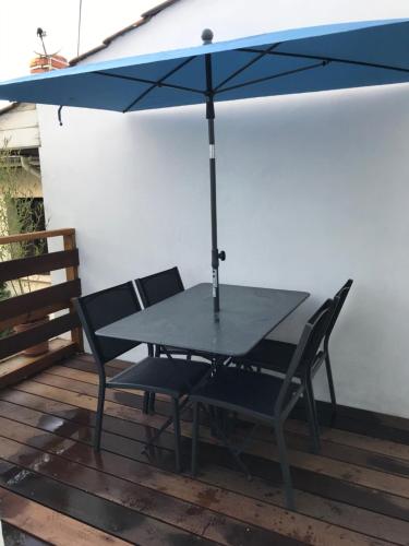 a table and chairs under an umbrella on a deck at Le Clos Beaufleury in Bordeaux