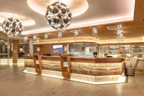 a bar in a hotel lobby with chandeliers at Wellness- & Sporthotel Jagdhof in Röhrnbach