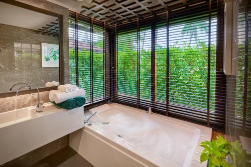 a bathroom with a tub and a large window at Khanom Beach Resort And Spa in Khanom