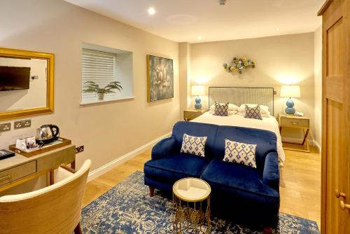 a bedroom with a bed and a blue couch at The Ormond At Tetbury in Tetbury