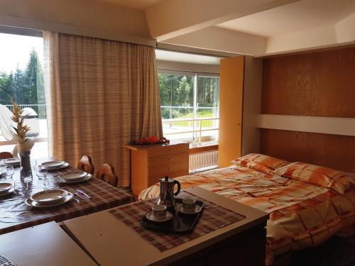 a bedroom with a bed and a table and a dining room at Res. Marilleva 1400 Apt.Solandra in Mezzana