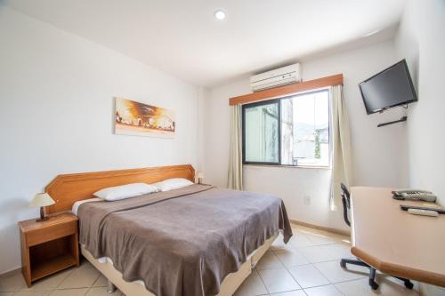 - une chambre avec un lit, une fenêtre et un bureau dans l'établissement OYO Residencial Itacuruçá Apart Hotel, à Itacuruçá