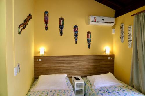 1 dormitorio con 2 camas y cabecero con zapatos en la pared en Pousada Manicaca, en Guarda do Embaú
