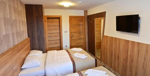 a hotel room with two beds and a flat screen tv at Pansion Winter in Jahorina