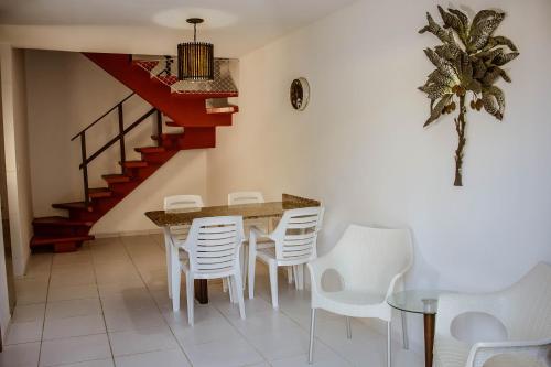 a dining room with a table and white chairs at Tamandare Residence in Tamandaré