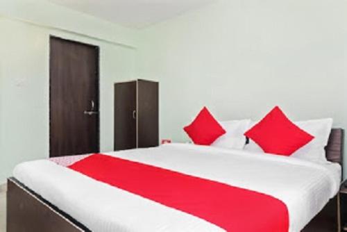 Hotel Nandanvan by Royal Stay في لونافالا: سرير كبير احمر وبيض مع مخدات حمراء