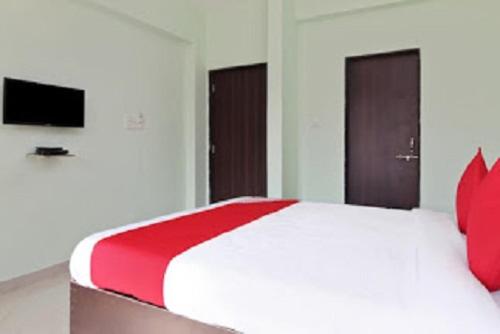 Hotel Nandanvan by Royal Stay في لونافالا: غرفة نوم بسرير كبير ومخدات حمراء