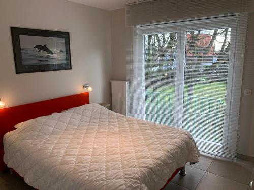 een slaapkamer met een bed en een groot raam bij Residentie Week-end Elisalaan in Nieuwpoort