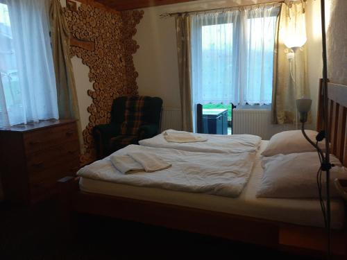 a bedroom with a bed and a chair and windows at Penzion Slovakia in Ždiar