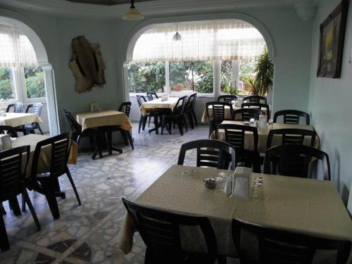 ein Esszimmer mit Tischen, Stühlen und Fenstern in der Unterkunft Hotel Anadolu in Finike
